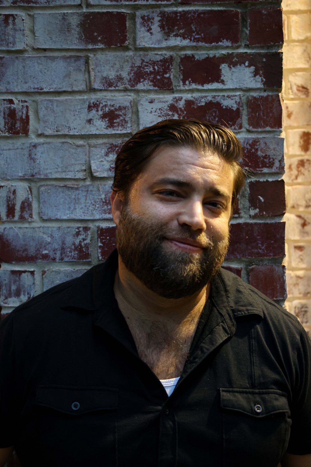 Portrait of Matt Long smiling against a weathered red brick wall